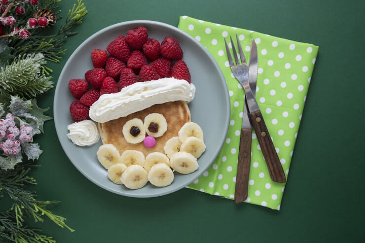 This image shows a stack of pancakes decorated to look like Santa.