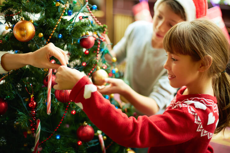 This image shows kids decorating a Christmas tree.